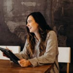 Girl sat at table holding ipad