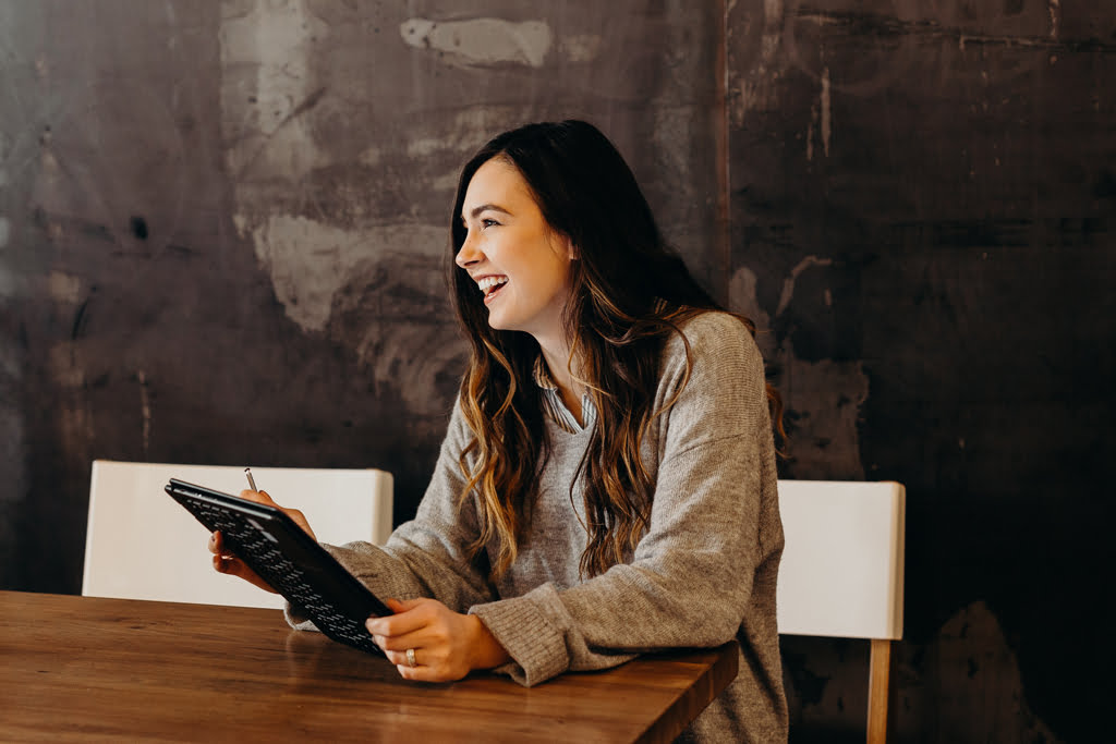 Girl sat at table holding ipad