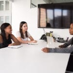 A femail having a job interview with two other people, sat around a table