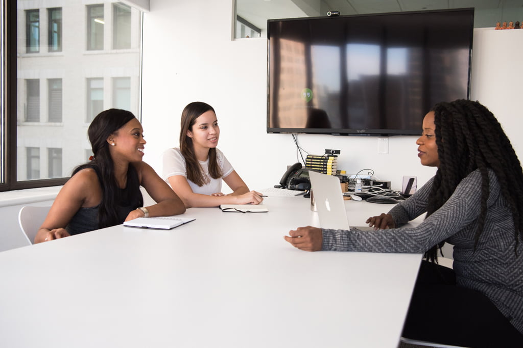 A femail having a job interview with two other people, sat around a table